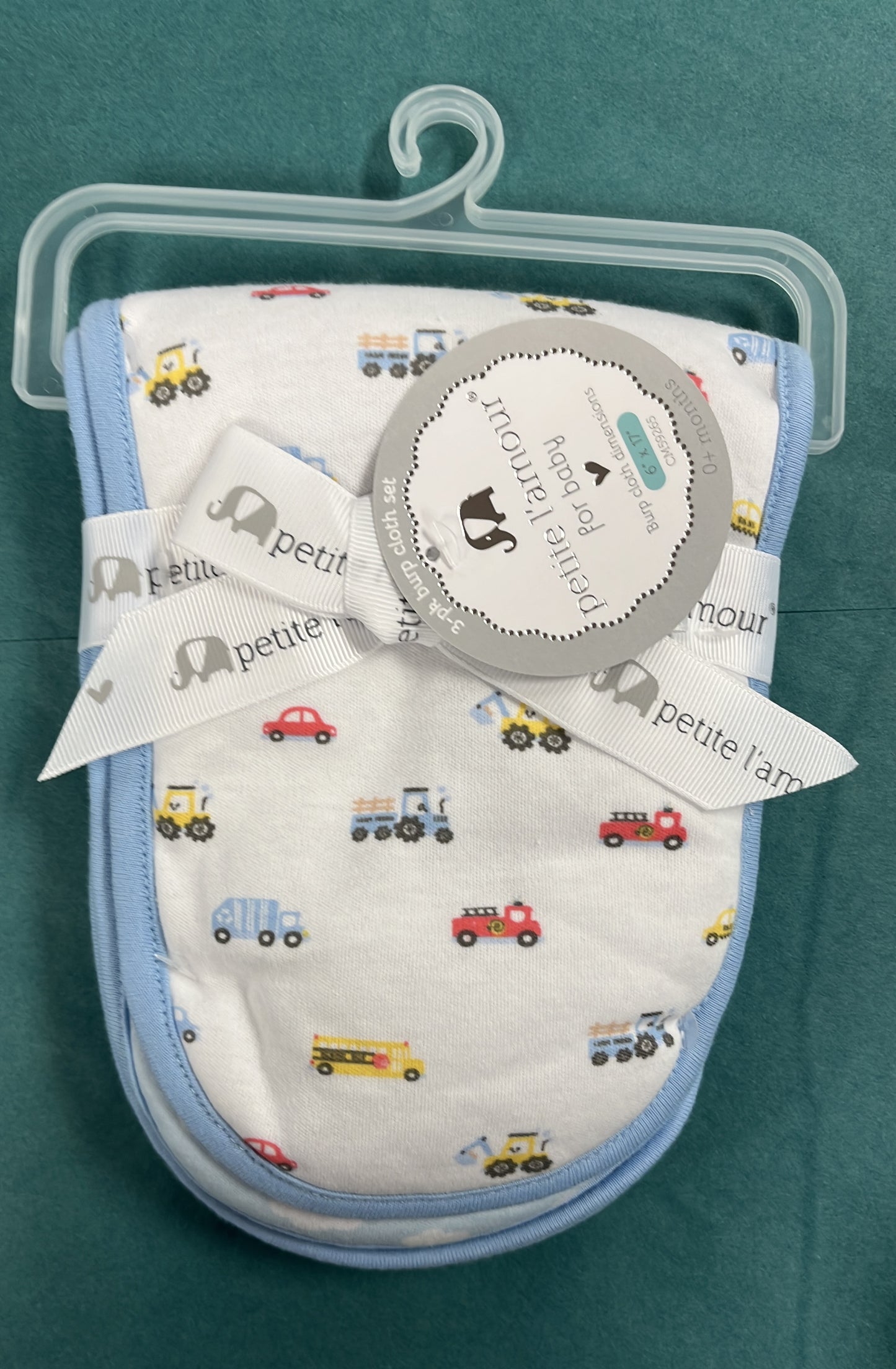 Baby bib set with vehicle pattern on a hanger against a teal background