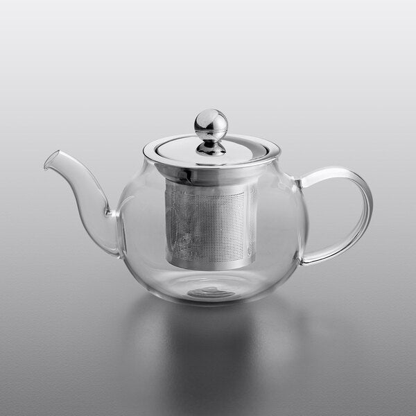Clear glass teapot with metal infuser and lid on a gray background