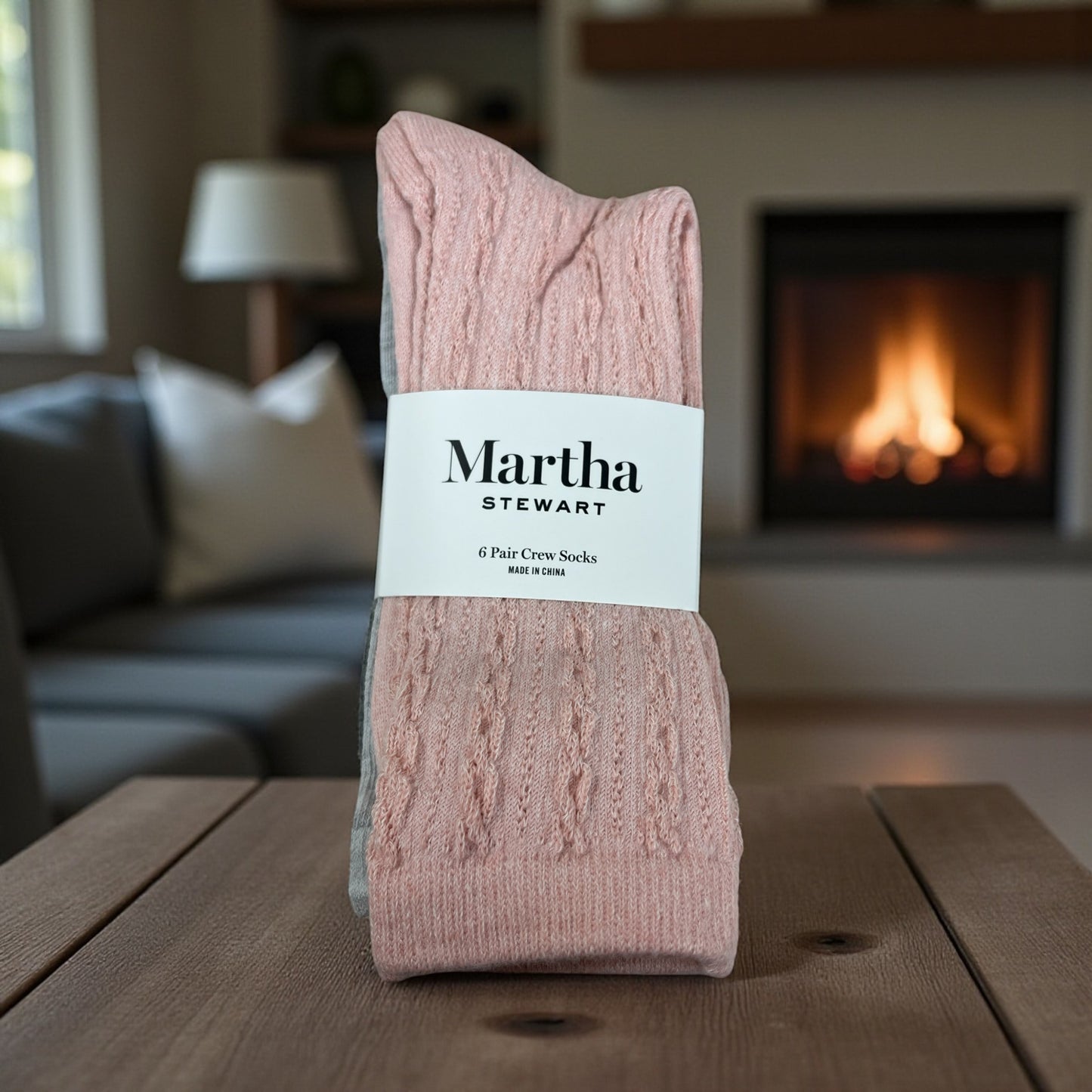 Pink socks with a Martha Stewart label on a wooden table in a cozy living room.