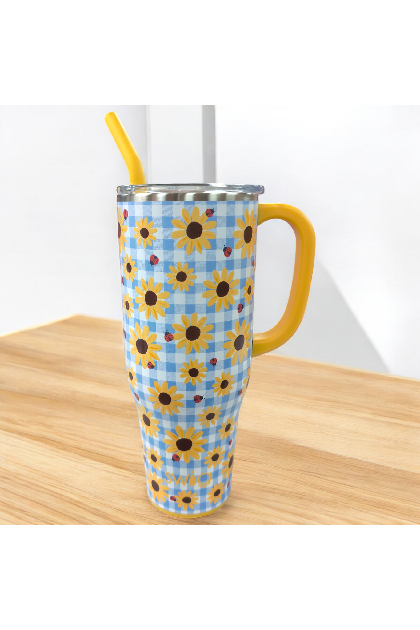 A 40oz stainless steel swig mug with a blue and white checkered pattern, featuring sunflowers and ladybugs, with a yellow handle and a straw hole on the top.