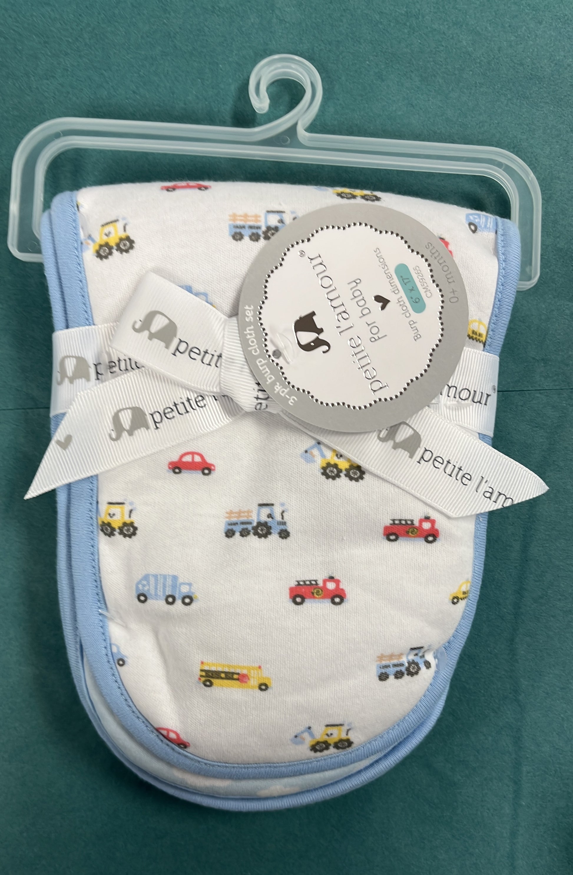 Baby bib set with vehicle pattern on a hanger against a teal background