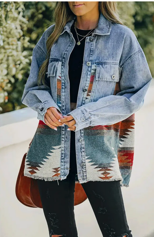 Person wearing a denim jacket over a patterned shirt with a blurred background