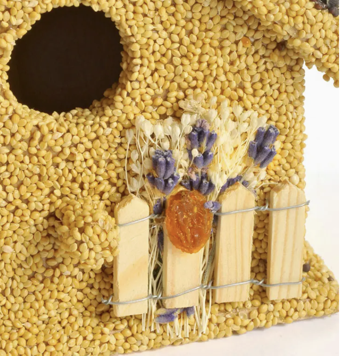Birdhouse made of yellow seeds with a small window and decorative elements on a white background