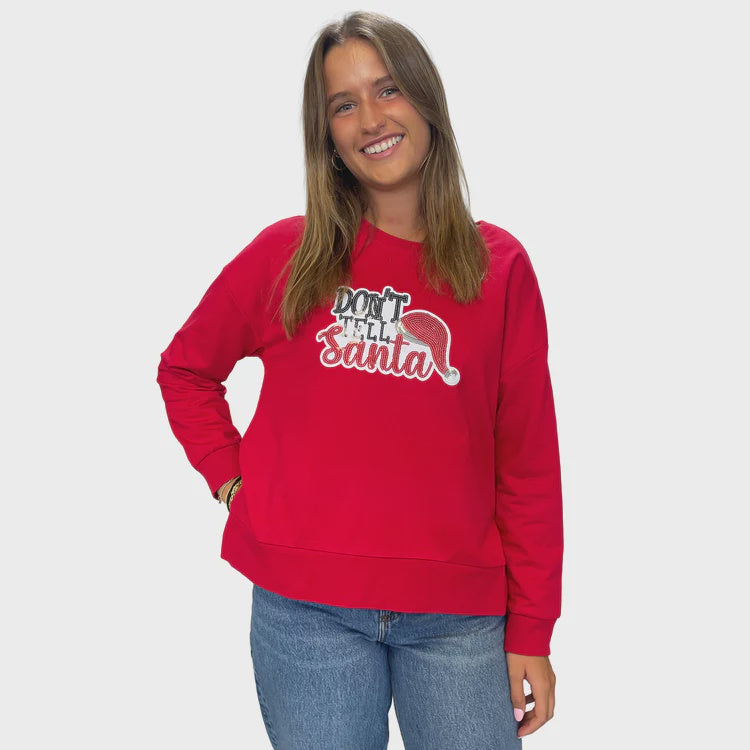 Person wearing a red sweatshirt with text and graphic design on a plain background