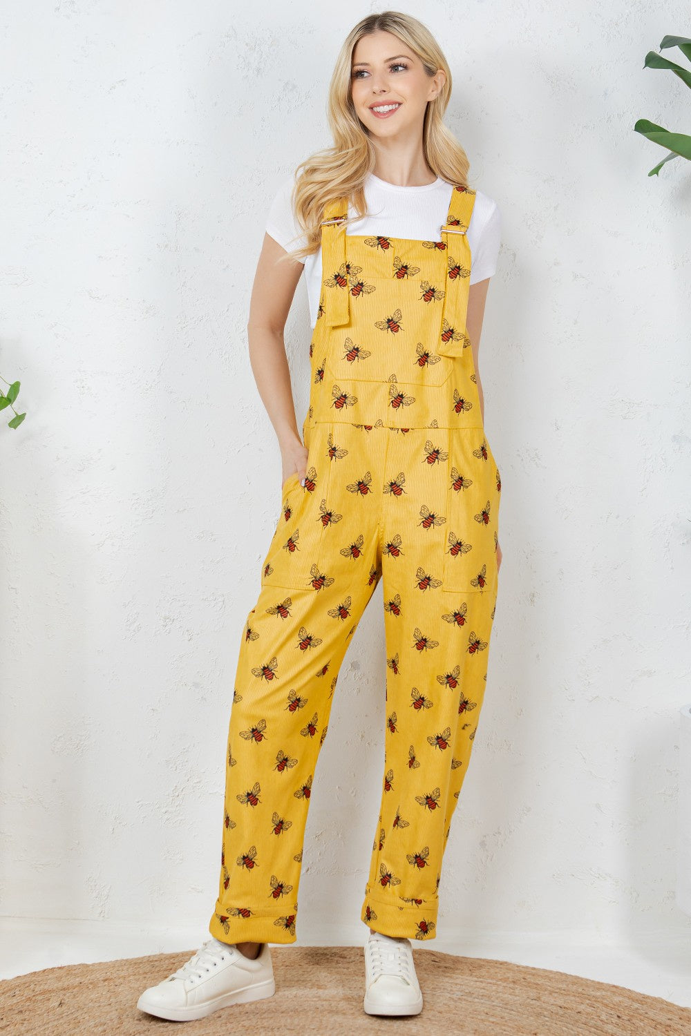 Woman wearing yellow patterned overalls on a white background
