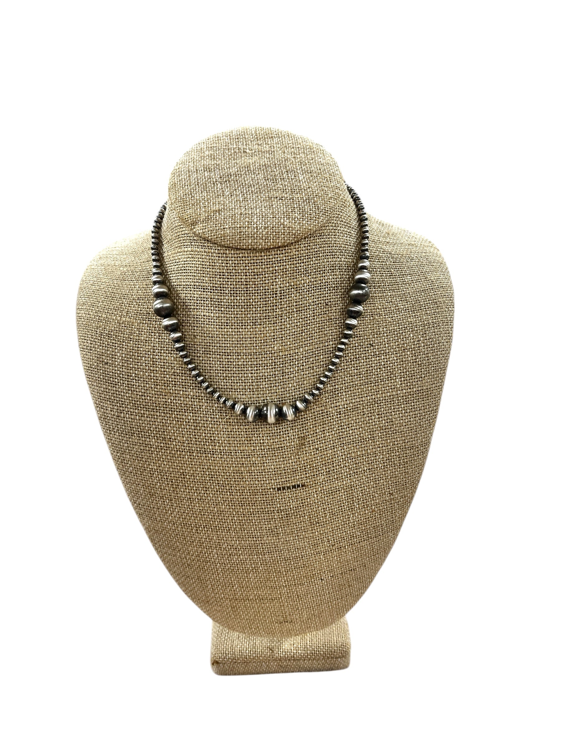 Necklace on a beige mannequin bust against a white background