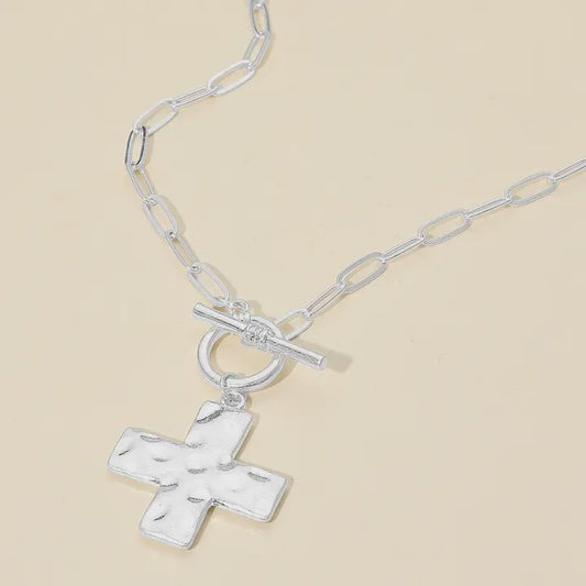 Silver necklace with a cross pendant on a beige background
