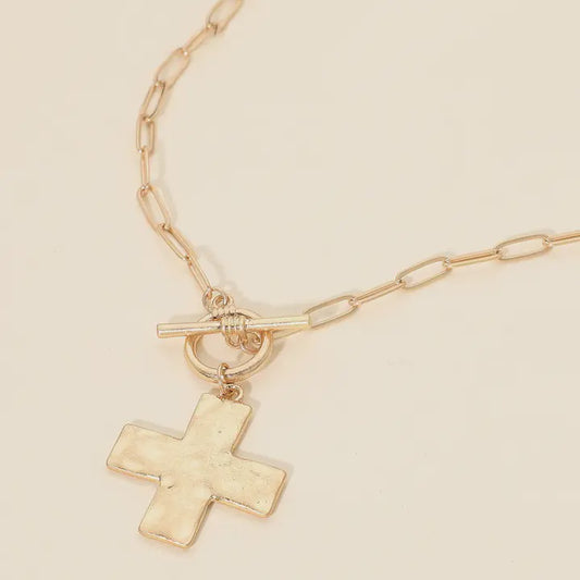 Gold chain necklace with a cross pendant on a beige background