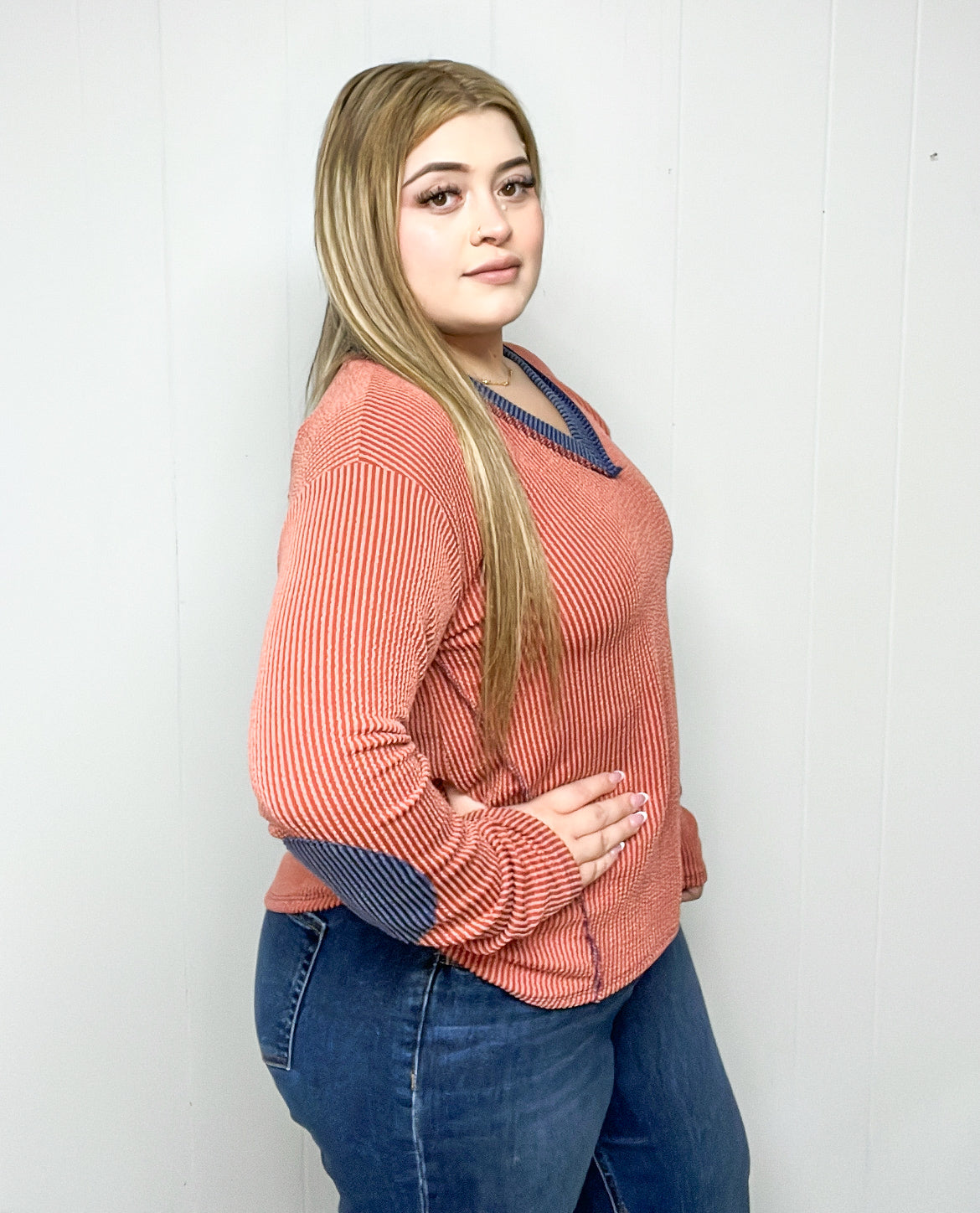 Woman wearing a pink sweater with blue accents against a white background