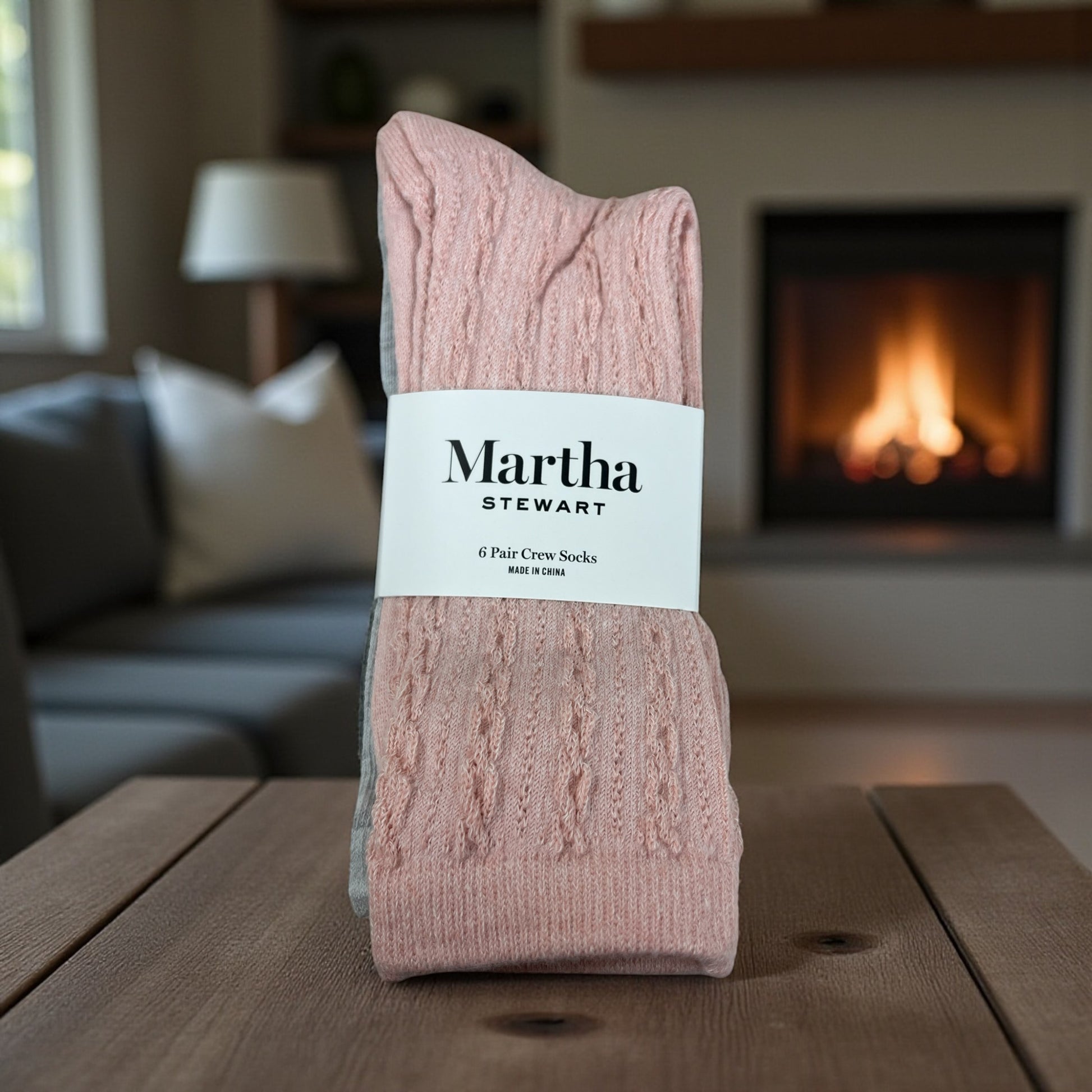 Pink socks with a Martha Stewart label on a wooden table in a cozy living room.