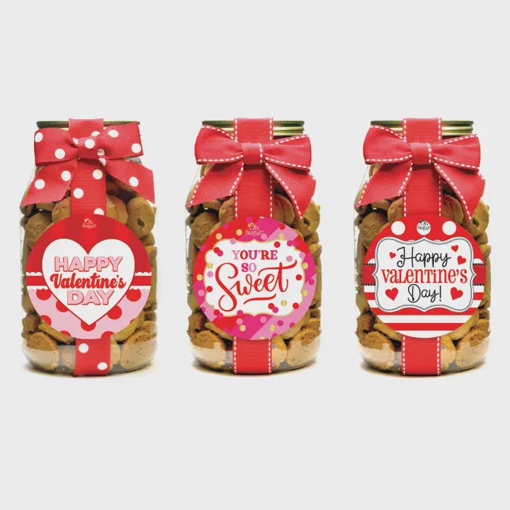 Three jars of cookies with Valentine's Day-themed labels and ribbons on a white background