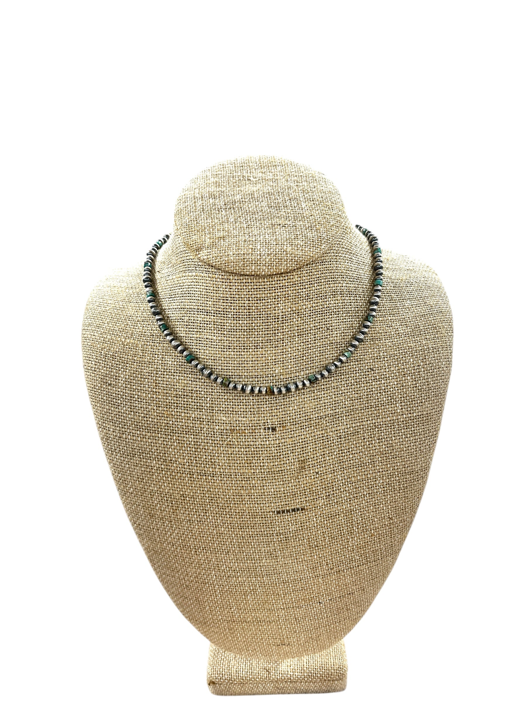 Necklace displayed on a beige jewelry stand against a white background
