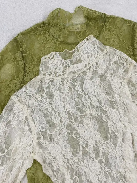 Close-up of a green lace garment with a white lace overlay on a light gray background.