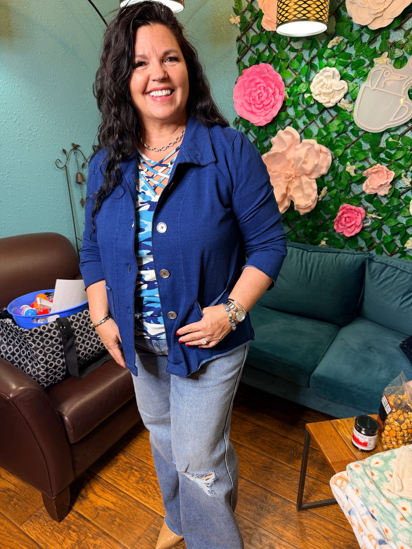 Woman sitting on a couch wearing a blue jacket in a room with decorative elements.