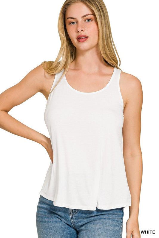 Woman wearing a white tank top and blue jeans on a plain background